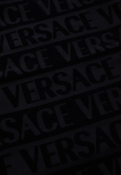 Juodas audinys su pakartotu "VERSACE" raštu, turinčiu iškilų tekstūrą, sukuriantis tonu ant tono efektą.