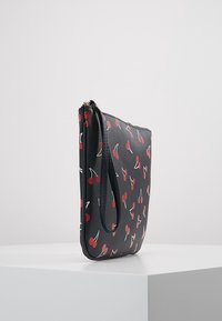 Pochette noire en synthétique avec motif cerises, dotée d'une fermeture éclair et d'une lanière latérale pour poignet. Texture lisse et design élancé.