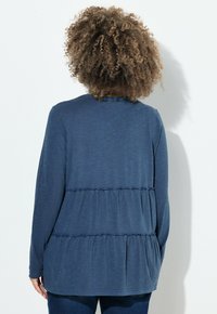 Langärmliges navy Top aus weichem Stoff, mit einem gestuften Rüschendesign und gerafften Nähten sowie einem runden Halsausschnitt.