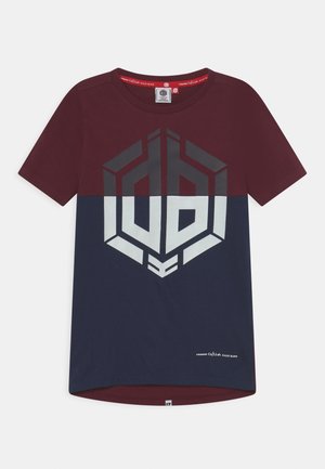 Kortærmet, tofarvet T-shirt i bordeaux og marineblå med en stor geometrisk hvid og grå logo på brystet og lille tekst ved kanten.