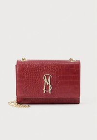 Rote Handtasche aus krokodilledergeprägtem Leder mit Klappdeckel, goldener Kettenriemen und auffälligem Metalllogo auf der Vorderseite.