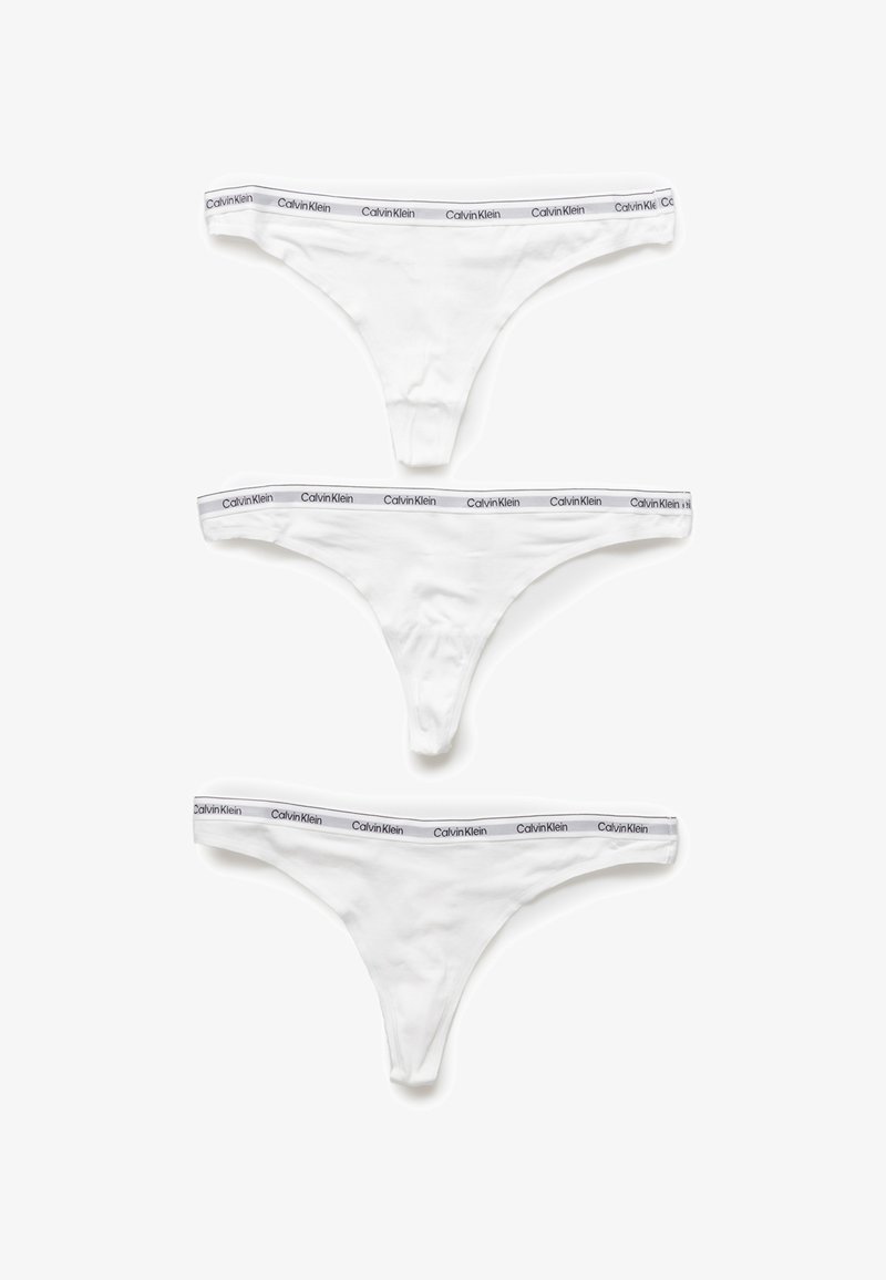 Tres tangas de algodón blanco con cinturilla de logo gris de Calvin Klein, que presentan una textura suave y un diseño minimalista.