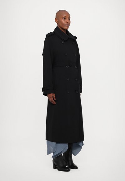 Mustat kaksiriviset trench-coat-hameet, joissa on leveä kaulus, vyö, ja polvimittainen muotoilu. Mukana pitkät hihat ja napitukset.