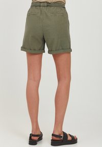 Olive green shorts with a rolled hem, featuring a gathered waistband and two back pockets. Worn with black strappy sandals.