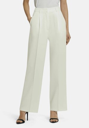 Wide-leg trousers in light cream, made from a smooth fabric. Features front pleats and side pockets, paired with black open-toe heels.
