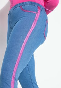 Blauwe denim jeans met een opvallende roze zijstripe, een getailleerde pasvorm, zakken met roze accenten en een gestructureerde afwerking.