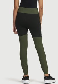 Hoch taillierte Leggings in Schwarz und Dunkelgrün. Hergestellt aus elastischem Material mit Farbblockedesign an den Beinen. Verfügt über eine Seitentasche und eine enge Passform.