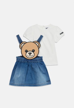 Hvid kortærmet top med puffærmer og denim nederdel med justerbare stropper med et stort bamseansigt foran.