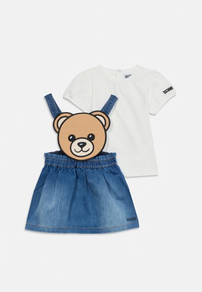 Haut blanc à manches courtes bouffantes et jupe en jean avec bretelles réglables, avec un grand visage d'ours en peluche sur le devant.