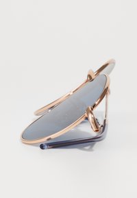 Ochelari de soare cu lentile supradimensionate albastre, ramă metalică de culoare aurie roz și vârfuri transparente albastre. Textură netedă cu hardware minim.