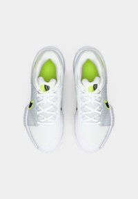 Λευκά αθλητικά παπούτσια με επάνω μέρος από πλέγμα, που διαθέτουν πράσινες λεπτομέρειες και υφασμάτινη σόλα. Οι κορδόνια είναι λευκά, και ο σχεδιασμός είναι κομψός με ένα λογότυπο.