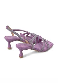 Lila Wildledersandalen mit hohen Absätzen, gekreuzten Riemen und glitzernden Akzenten. Sie haben eine quadratische Zehenpartie und einen kurzen, stabilen Absatz.