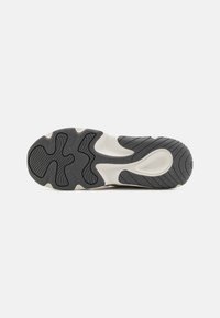 Gummisåle til sneakers med et grått og hvitt fargevalg, med en teksturert overflate og spor for bedre grep.
