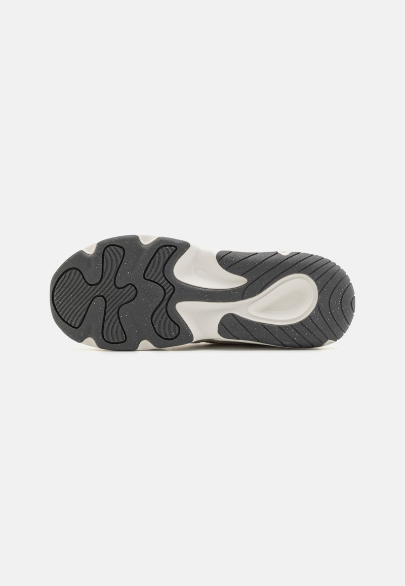 Semelle de sneaker en caoutchouc avec un schéma de couleurs gris et blanc, comportant un motif texturé et des rainures pour l'adhérence.