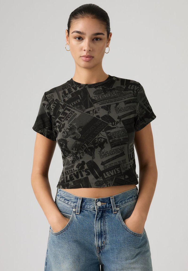 Κοντοκομμένο μαύρο γραφικό t-shirt με διάφορα ασπρόμαυρα τυπωμένα σχέδια. Κοντά μανίκια και στρογγυλή λαιμόκοψη. Συνδυασμένο με ανοιχτόχρωμα τζιν σορτς.