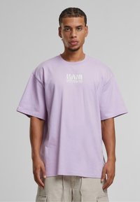 Lavender short-sleeve t-shirt made of cotton, featuring a printed "KANI STUDIOS" logo on the chest. Relaxed, boxy fit.