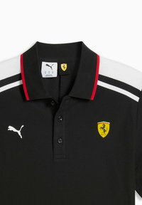 Polo noir avec des accents rouges et blancs, doté d'un col, de trois boutons, et d'un logo Ferrari jaune sur le côté gauche de la poitrine. Logo Puma présent.