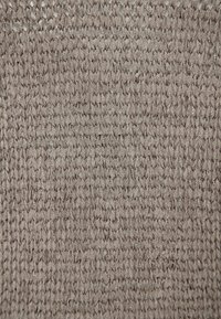 Texturiertes Strickgewebe in einem hellen Taupe-Ton, das ein offenes Webmuster mit ineinandergreifenden Schlaufen aufweist und ein weiches sowie luftiges Erscheinungsbild schafft.