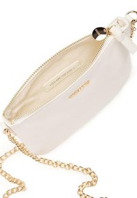 Funda de cuero blanco con cremallera dorada y correa de cadena. El interior presenta una etiqueta que dice "ERES EL SOL". Textura suave, diseño minimalista.