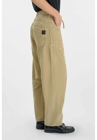 Khaki wijde corduroy broek met een gestructureerd patroon, voorzien van achterzakken en een logo-opdruk. De tailleband heeft een trekkoorddetail.