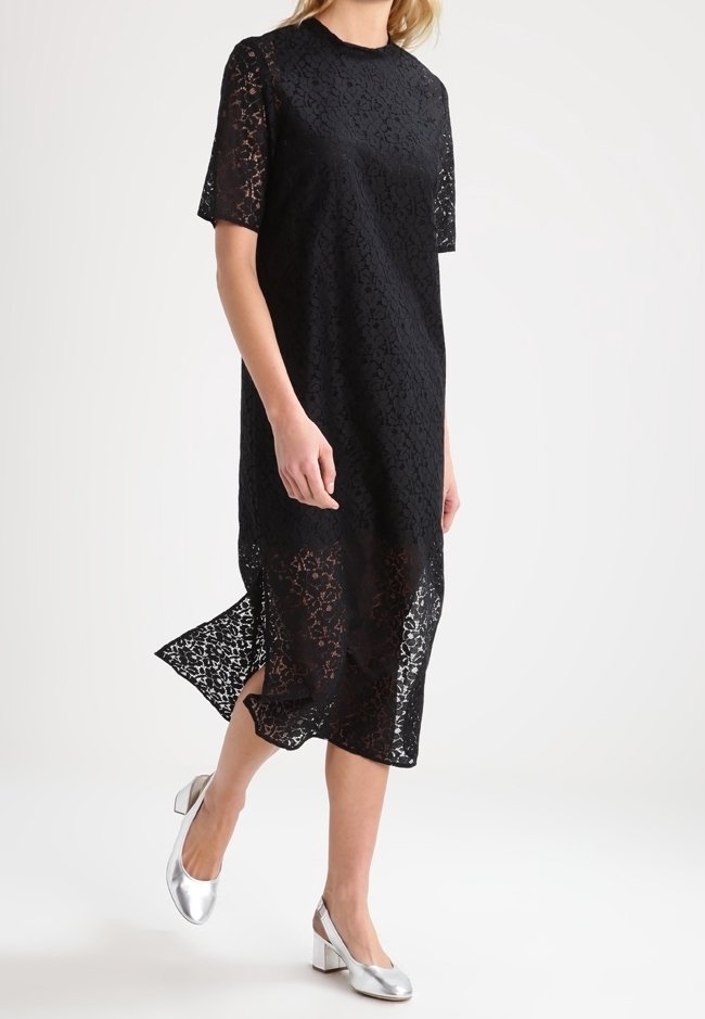 Svart spetsklänning med korta ärmar, rund halsringning och sidoklyvning. Matchad med silverfärgade blockklackskor. Strukturerad spetsmönster.