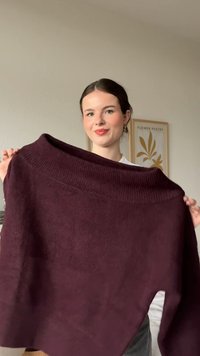 Bordowy, oversize sweter z prążkowanym dekoltem, miękką fakturą i bocznymi rozcięciami. Tkanina wydaje się dzianinowa, co zwiększa komfort i styl.