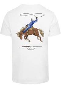 Hvit T-skjorte med en detaljert illustrasjon av en rytter på en brun hest, med lasso i hånden, og teksten "LEV I ØYEBLIKKET" under.