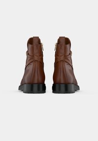 Brown leather ankle boots with a smooth texture, featuring a black rubber sole and a decorative zipper on the back.