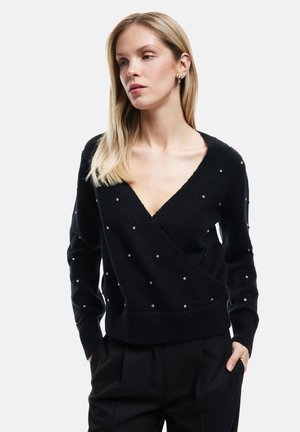Black wrap sweater made of soft fabric, featuring a deep V-neck, embellished with small silver accents evenly spaced across the surface.