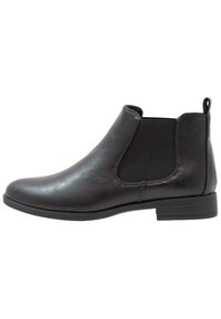 Bottine en cuir noir avec panneaux élastiques sur les côtés, bout arrondi et un petit talon empilé. Texture lisse avec une languette à l'arrière.