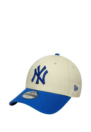 Cappellino da baseball beige e blu dei New York Yankees con logo ricamato e visiera curva, mostrato leggermente inclinato su sfondo bianco.