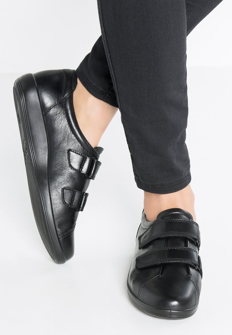 Scarpe in pelle nera con punta arrotondata, dotate di due cinturini regolabili. Il design presenta una superficie liscia e una suola a profilo basso.