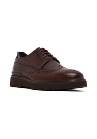 Chaussure brogue en cuir marron foncé avec des panneaux textur�és, des motifs décoratifs perforés, un laçage et une semelle en caoutchouc épaisse.