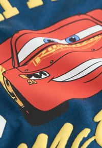 Red car graphic featuring character with blue eyes, number 95, and yellow text on a blue background; smooth texture and vibrant colors.
