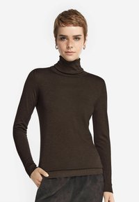 Brun polotröja i ett mjukt, stretchigt material, med l�ånga ärmar och en åtsittande design, i kombination med en texturerad svart underdel.