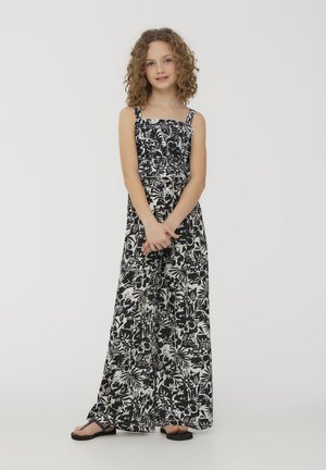 Jumpsuit a stampa floreale in bianco e nero con spalline regolabili, corpetto arricciato e pantaloni a gamba larga. Il materiale sembra leggero e ha una texture morbida.