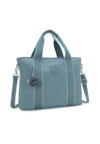 Teal tote bag made of textured material with beige accents, featuring two handles, a removable shoulder strap, and a furry charm.
