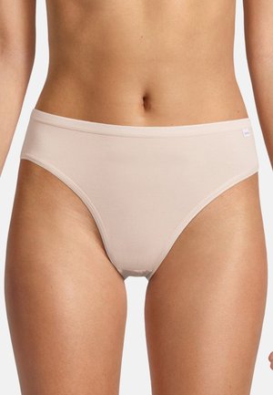 Vrouw draagt beige naadloos ondergoed, met zicht op de buikstreek en bovenbenen tegen een witte achtergrond.