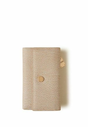 Portefeuille rectangulaire beige texturé avec une fermeture circulaire dorée et une petite étiquette sur le côté droit sur un fond blanc.