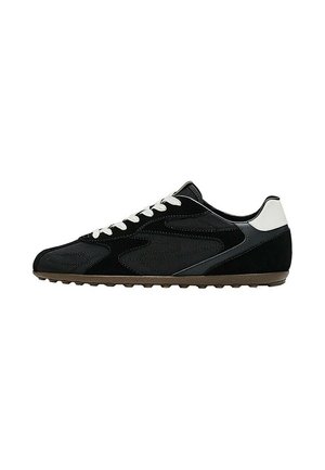 Sneaker basso nero e grigio con lacci bianchi e linguetta sul tallone, suola testurizzata e design cucito discreto sul lato.
