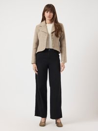 Beige karierter, kurzer Blazer mit drei Knöpfen, kombiniert mit weit geschnittenen schwarzen Hosen und olivgrünen Absätzen; glatte Texturen und taillierte Passform.