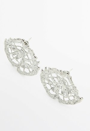 Oorbellen met winkelhaakpatroon in zilverkleurige onregelmatige mesh met een gestructureerd, open ontwerp tegen een witte achtergrond.