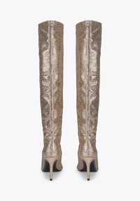 Knee-high gouden laarzen bedekt met kleine studs, met een slank ontwerp, puntige stiletto-hakken en een ritssluiting aan de achterzijde.