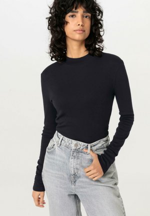 Langarm, getailleerd shirt in effen marineblauw, gemaakt van zachte stof. Draag het met hoog-getailleerde, lichtgewassen jeans met een klassiek vijf-pocket ontwerp.