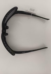 Czarne sportowe okulary przeciwsłoneczne z zakrzywionymi ramionami i regulowanymi noskami, wystawione na białej powierzchni.