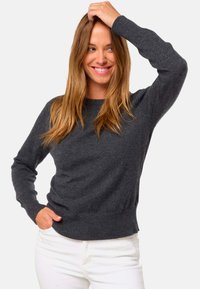 Pull en tricot gris avec un col rond, des manches longues et des poignets côtelés. Fabriqué en tissu doux avec une finition légèrement texturée.