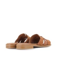 Sandalias deslizantes de ante marrón con diseño de cortes, suela de madera plana y textura suave. Presenta acentos minimalistas para un aspecto moderno.