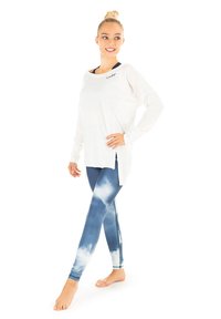 Loungewear sæt med en løs hvid langærmet top og blå leggings med sky-mønster. Stoffet ser blødt og åndbart ud.