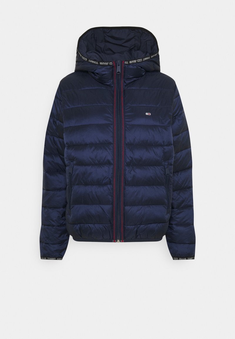 Marineblauwe gewatteerde pufferjack met capuchon, rits aan de voorkant, ritszakken aan de zijkanten en een klein logo op de borst.