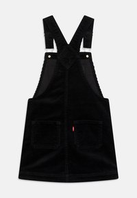 Černé kordurové šaty s kšandami na zádech, které lze nastavit, a dvěma předními kapsami. Mají jemnou žebrovanou strukturu a malou logo nášivku.